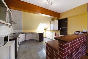 A kitchen with a corner island, white appliances, and a wooden ceiling.