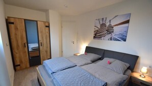 Un dormitorio con cama, mesita de noche, armario de madera y un cuadro colgado en la pared.