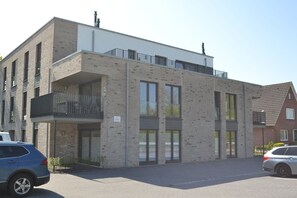 Moderni rakennus, jossa on tiiliverhous, suuret ikkunat ja parveke.