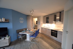 A modern kitchen with a dining area, a TV, and a seating arrangement.