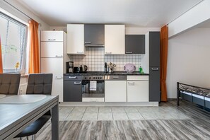 Une cuisine compacte avec un coin repas, un four encastré et une petite table à manger.