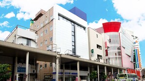 Un edificio de varios pisos con una estructura roja y blanca llamativa, un paseo techado y diversos comercios.
