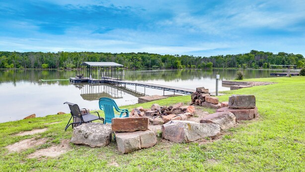 A lakeside dock with a covered seating area, a chair, and a fire pit. - Lake of the Ozarks Cabin w/ Private Dock + Kayaks (Lincoln)