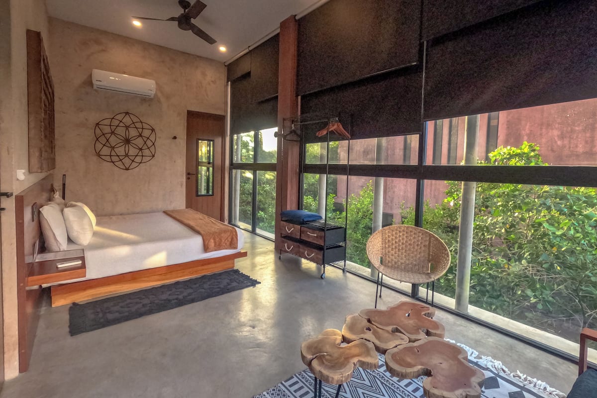 A modern bedroom with a large window, a ceiling fan, and a bed with a wooden headboard.