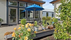 Een terras met tuinmeubilair, een blauwe parasol en planten in potten.