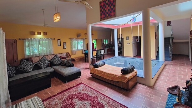 Un salon spacieux avec un canapé, une table basse et un tapis à motifs. On y trouve également un ventilateur de plafond et une fenêtre avec des rideaux.