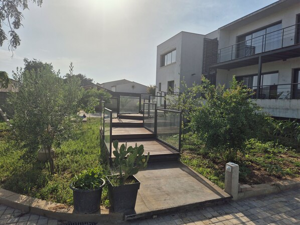 Un bâtiment moderne doté d’un pont de verre qui mène à un jardin sur le toit.