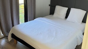A bedroom with a bed, curtains, and a view of the outdoors. - 2-room luxury apartment  (Juvignac)