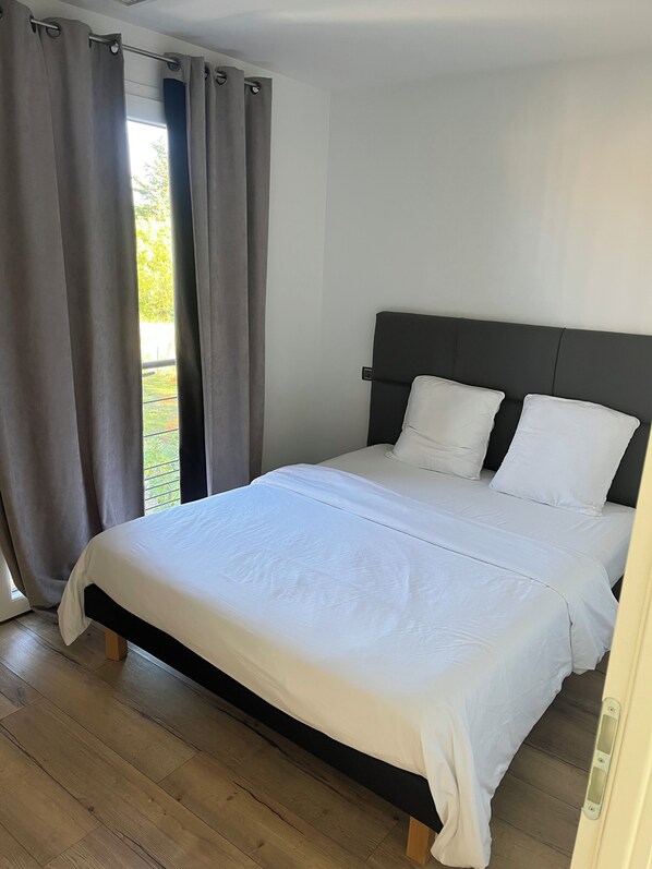 Une chambre à coucher avec un lit, des rideaux et une vue sur l’extérieur.