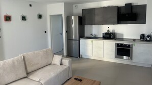 A modern kitchen with stainless steel appliances, a built-in oven, and a microwave. - 2-room luxury apartment  (Juvignac)