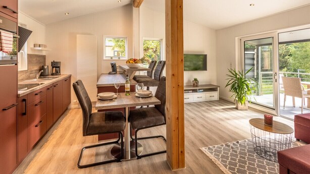 Une cuisine moderne avec un coin repas, un téléviseur et un balcon agrémenté d’une plante.