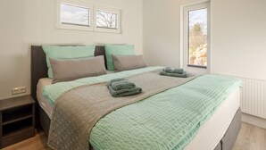 Une chambre à coucher avec un lit, deux fenêtres et une vue sur l’extérieur.
