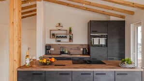 A modern kitchen with dark cabinets, wooden beams, and a built-in oven. - Chalet Seeblick I Terrace I View I Hiking (Hillesheim)