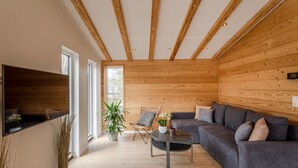 A modern living room with a wooden ceiling, a grey sofa, a round coffee table, and a large window. - Chalet Seeblick I Terrace I View I Hiking (Hillesheim)