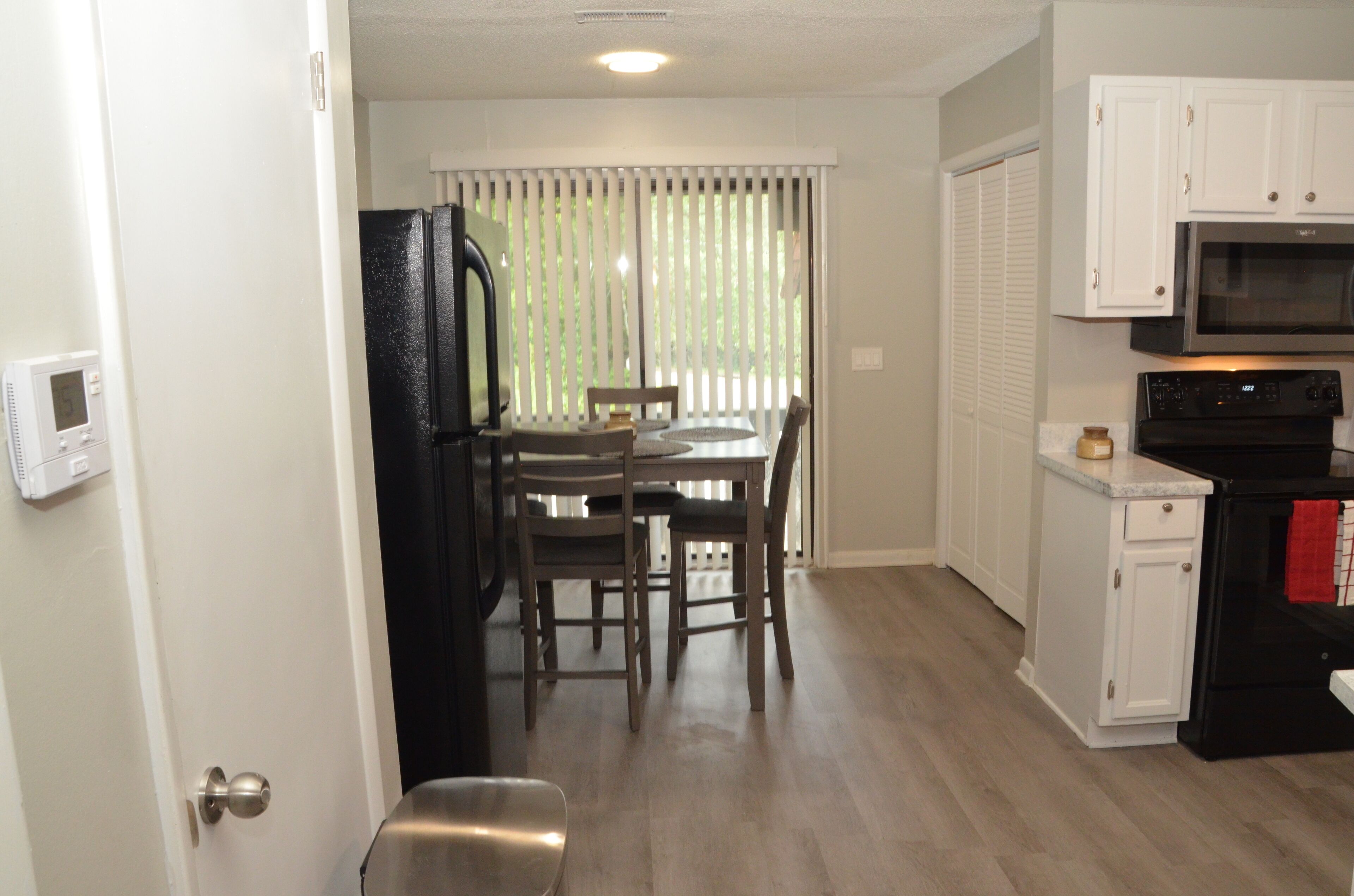 A compact kitchen with a refrigerator, microwave, oven, and a dining area with a table and chairs.