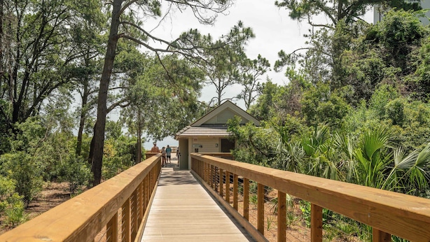 A wooden boardwalk leading to a building with a gabled roof, surrounded by dense greenery. - Steps to Beach | Pool | Pet Friendly | Sleeps 8 | Hilton Head (Hilton Head Island)
