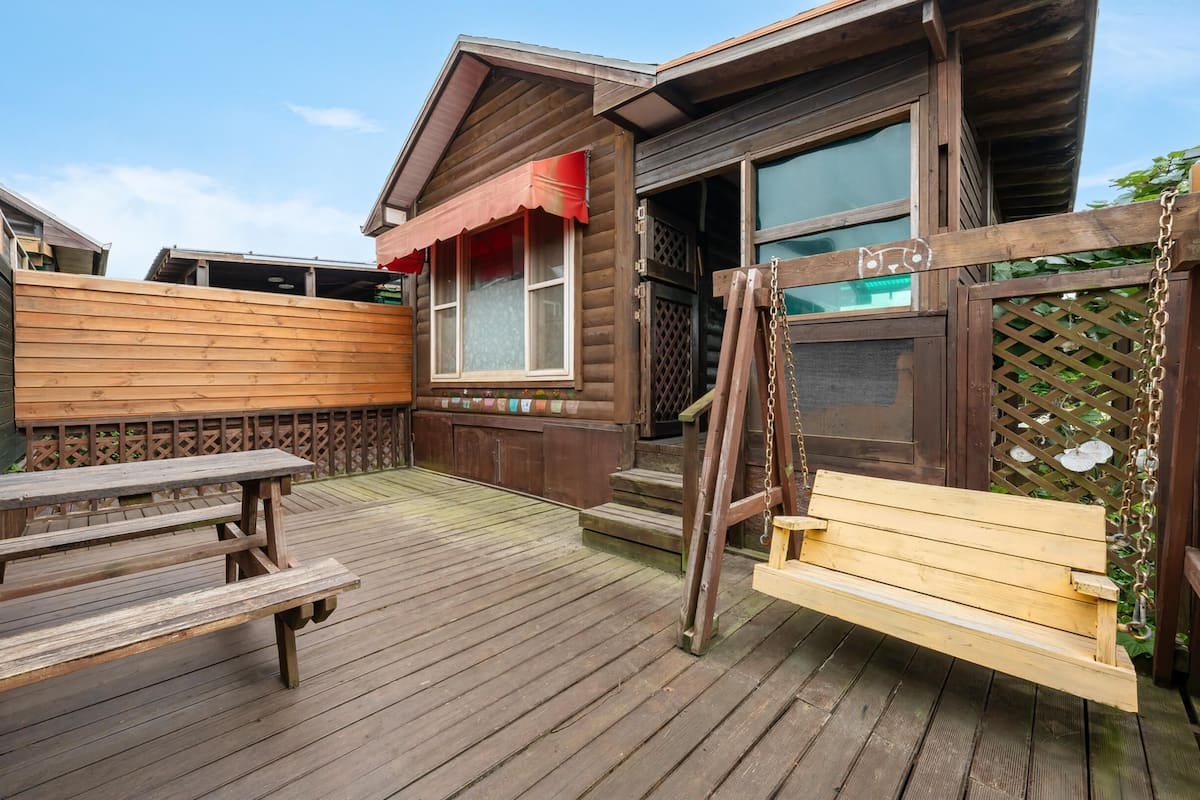 A wooden deck with picnic tables and a swing.