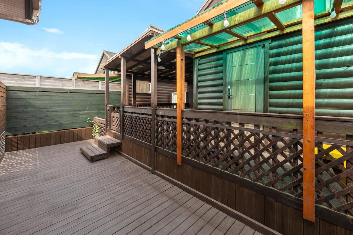 A wooden deck with a wooden fence and a covered area with a green roof.