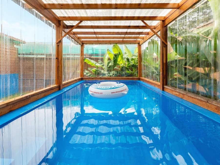 An indoor swimming pool with a clear view of the surrounding landscape through large windows.