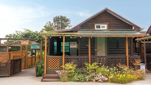 A wooden cabin with a porch, a small window, and a door. - Boryeong Hiddenvillage Dokchae Poolvilla (Boryeong)