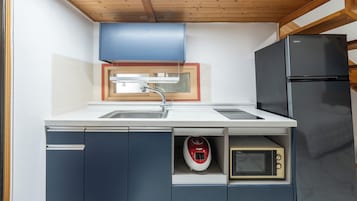Una cocina funcional con lavamanos, microondas y refrigerador.