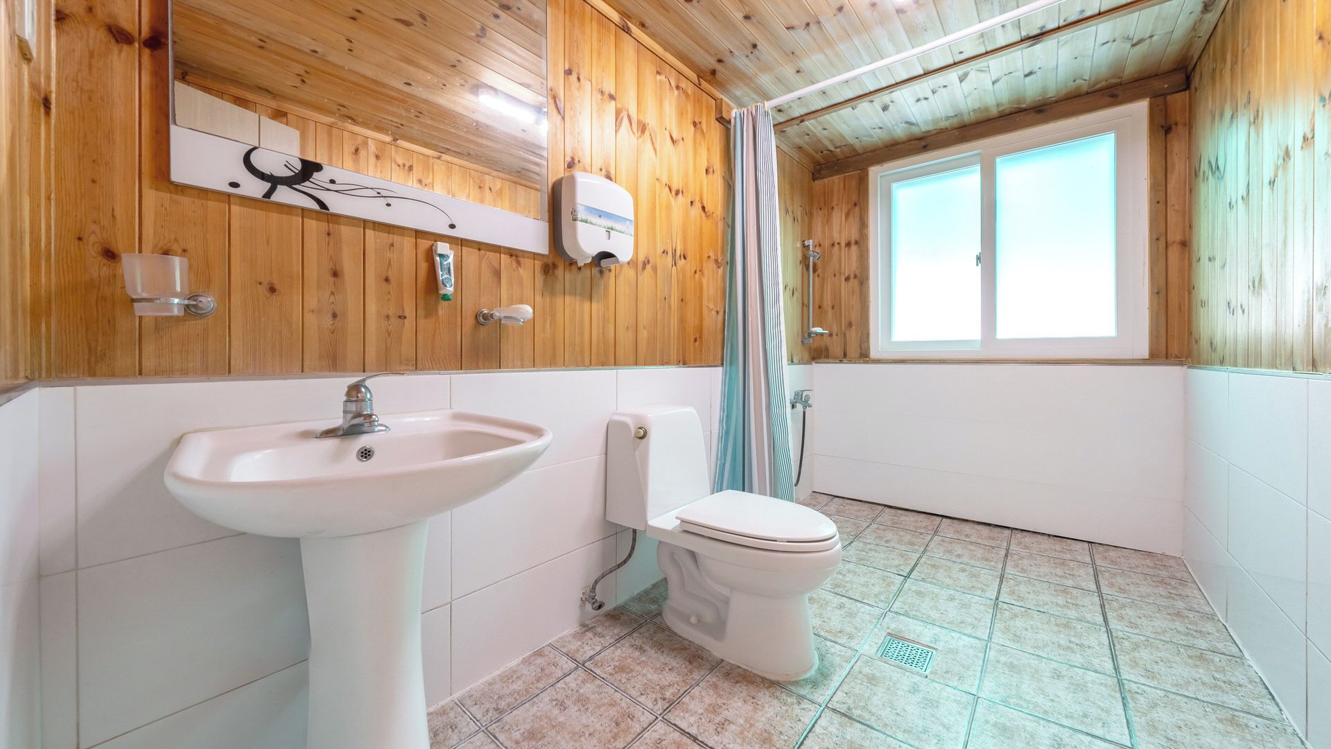 A bathroom with a sink, toilet, and a window with a view.