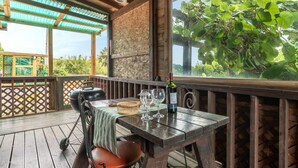A wooden deck with a table set for two, a grill, and a bottle of wine. - Boryeong Hiddenvillage Dokchae Poolvilla (Boryeong)