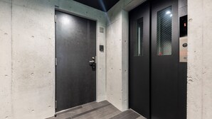 Un ascenseur moderne, doté d’une finition métallique et d’un panneau de commande avec des flèches indiquant les directions.