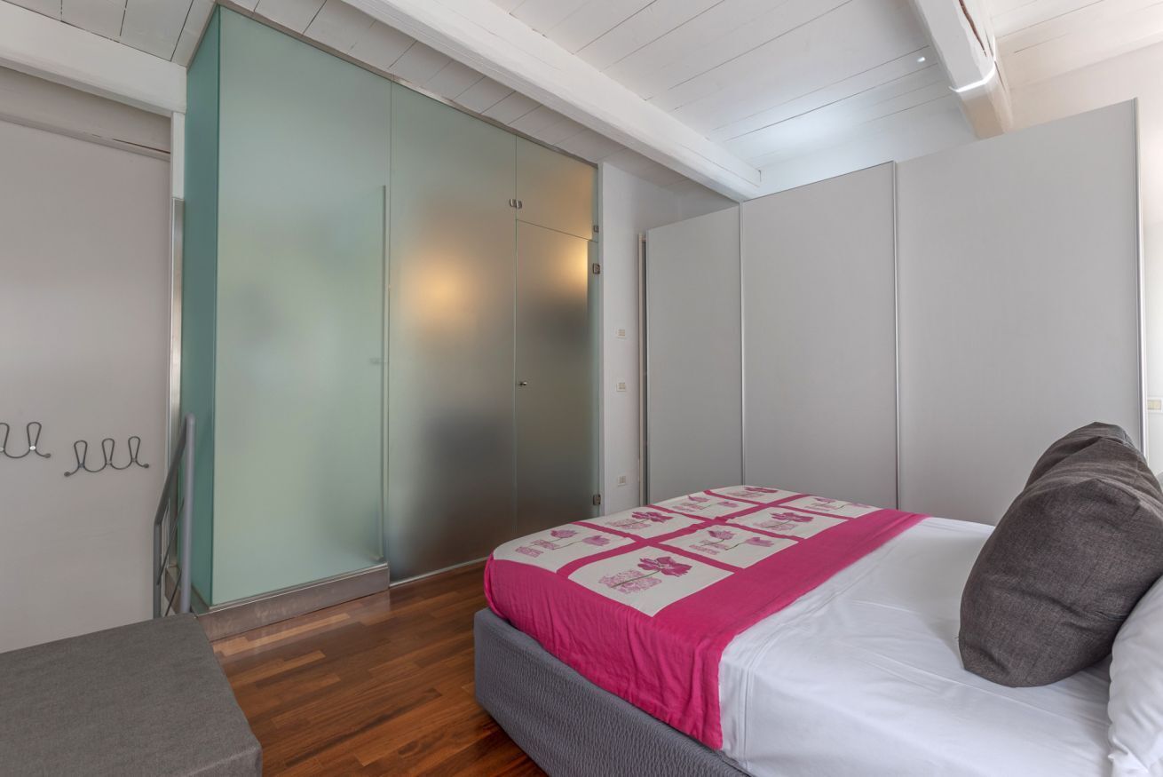 Una camera da letto con un letto, una panca, un armadio e una porta scorrevole.