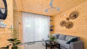 Un interior de madera con un sofá gris, una mesa pequeña con una planta y un ventilador de techo.