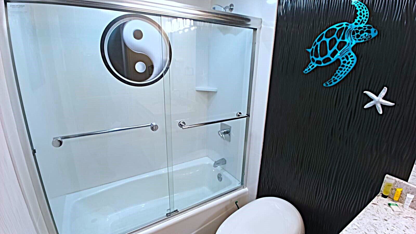 Kylpyhuoneessa on lasiseinällä varustettu suihku, wc ja seinä, joka on koristeltu kilpikonnalla ja meritähdellä.