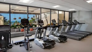 Un gimnasio con cintas de correr, bicicletas estáticas y una máquina de remo.