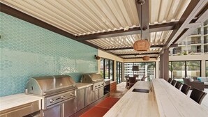 Una cocina moderna con electrodomésticos de acero inoxidable, una mesa larga de comedor y vistas al exterior.