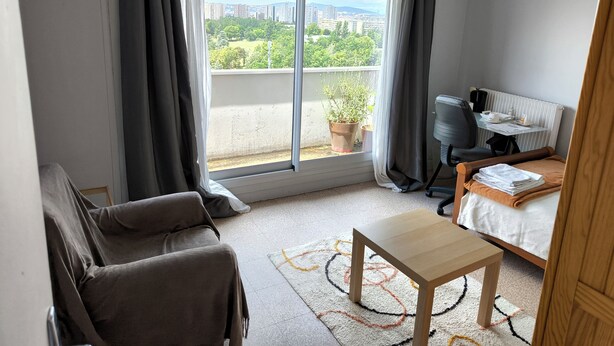 Habitació d'hotel moderna amb un balcó, un sofà, una taula petita i un llit.