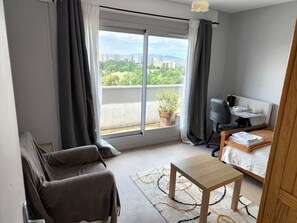 Une chambre d’hôtel moderne avec un balcon, un canapé, une petite table et un lit.