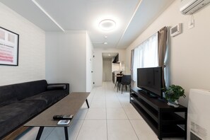 Relax in this stylish living room with a sofa, flat-screen TV, and a small potted plant.