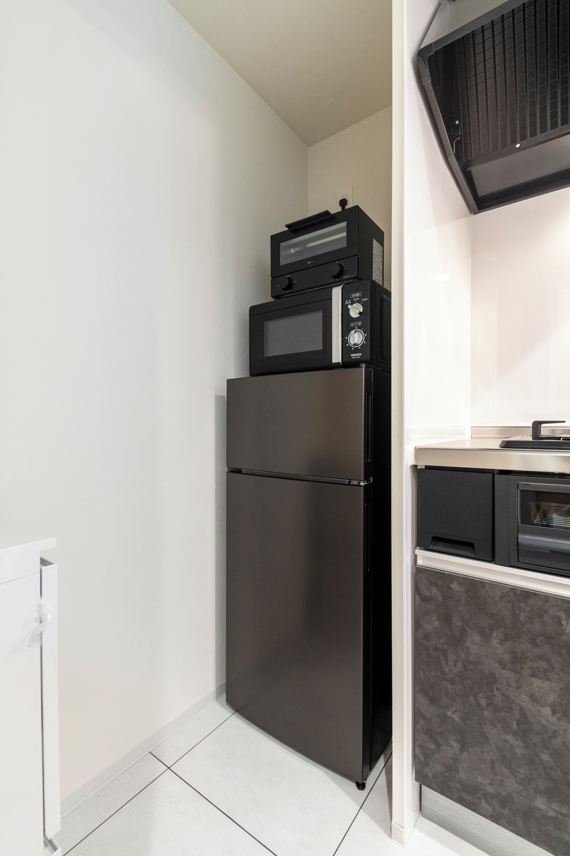 A compact kitchen with a black refrigerator, a microwave, and a built-in oven.