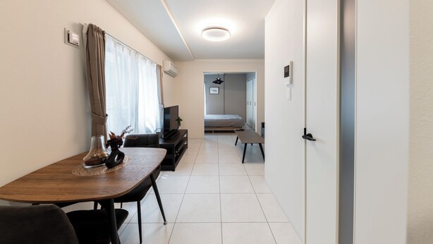 Una habitación de hotel moderna con una mesa de comedor de madera, un sofá, un televisor y una cama.
