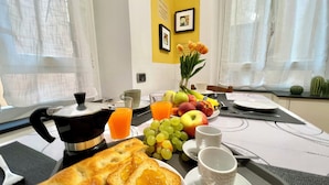 A breakfast setup with toast, fruit, and orange juice on a tray, with a coffee pot and cups on the table. - Happy Family Apartments Andreana (Genoa)