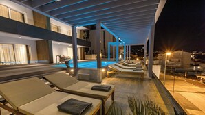 A modern outdoor pool area with lounge chairs and a covered seating area.
