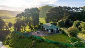 Ein eingeschossiges Haus mit grüner Dachbegrünung, umgeben von üppiger Vegetation und Hügeln im Hintergrund.