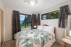 Une chambre à coucher avec un lit, une fenêtre, des rideaux, une table de chevet et une lampe.