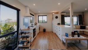 Eine moderne Küche mit einem großen Fenster, ein Essbereich mit einem Tisch und ein Wohnzimmer mit einer Couch.