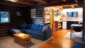 A log cabin interior with a living area, a kitchenette, and a dining area. - Totara Lodge | Snow | Couple Retreat - ML97564 (Mount Lyford Village)