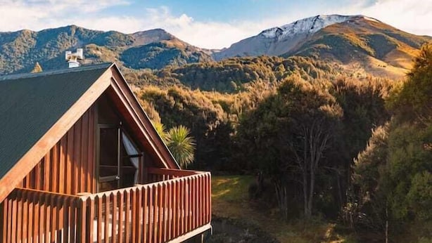 A wooden cabin with a balcony overlooking a mountainous landscape. - Totara Lodge | Snow | Couple Retreat - ML97564 (Mount Lyford Village)