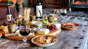 Una tabla de embutidos con diversos quesos, frutas y galletas sobre una mesa de madera.
