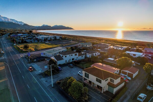 An aerial view of a coastal town with a road, residential buildings, and a beach.