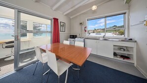 A modern kitchen with a wooden table and chairs, a microwave, and a sink. - Waterfront | Handy Location | Affordable | Unit 1 - KK41164 (Kaikoura)