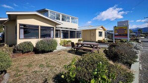 A two-story motel with a patio area, large windows, and a sign advertising the Seaview Motel. - Waterfront | Handy Location | Affordable | Unit 1 - KK41164 (Kaikoura)