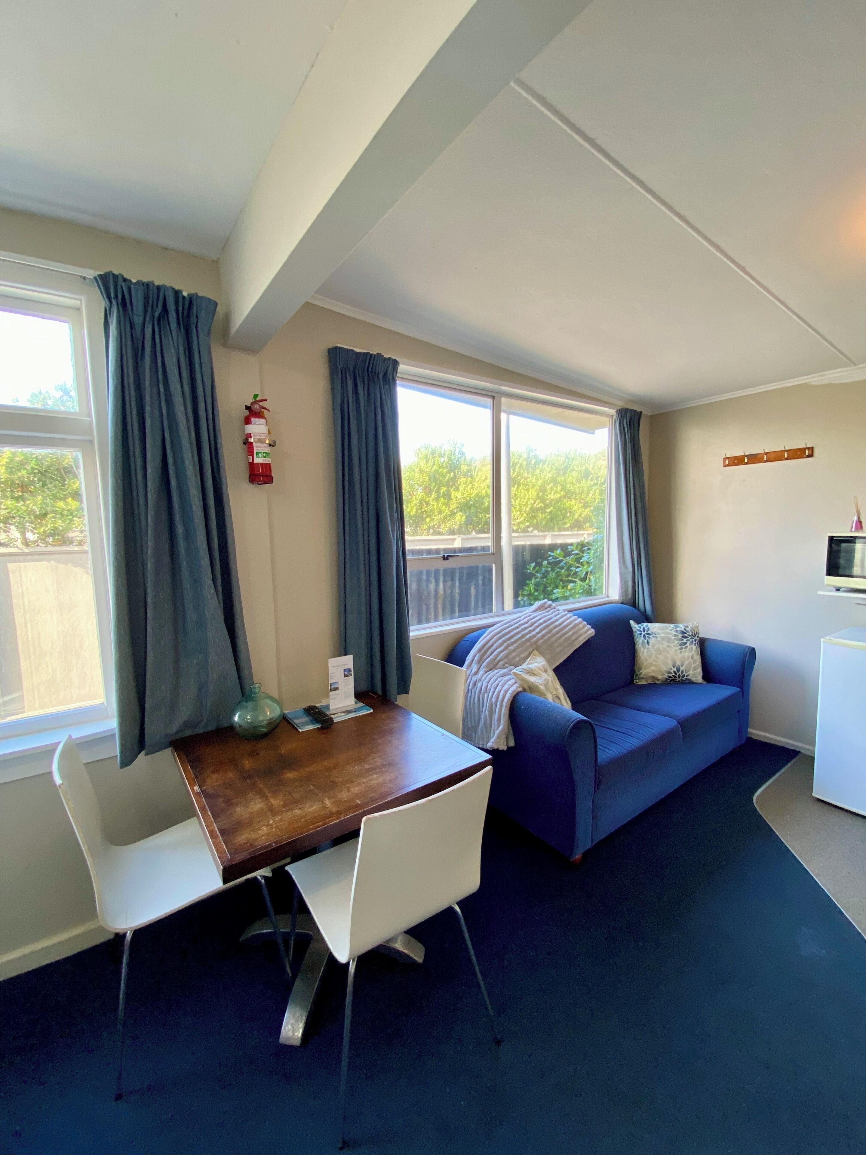 A compact living space with a dining table, two white chairs, a blue sofa, and a small white cabinet.